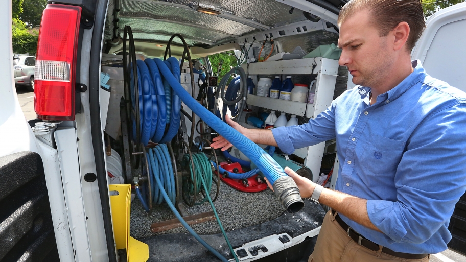 carpet cleaner holding truck-mounted hose